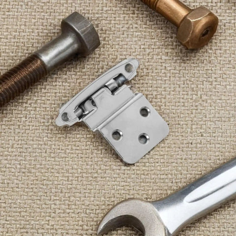 Close-up of No Slam Soft Close Frameless Inset Cabinet Hinge on textured surface with bolts and wrench