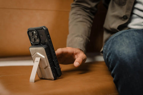 Black Titanium Two Port USB C Magnetic Wireless Portable Charger With 10000mAh Battery On The Go, attached to phone with kickstand.