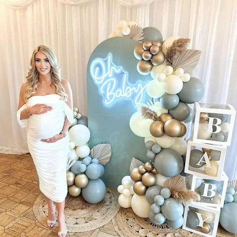 Neon Sign for Baby Shower Backdrop LED Light Up Wall Decor 21.5 Inch By 20 Inch Great for Gender Reveal Birthday Party Decorations Oh Baby Theme Great for Bedroom Walls and Photo Backdrops, displayed amidst balloons and cubes spelling 'BABY' with a pregnant woman posing.
