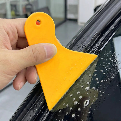 Using yellow plastic scraper from All In One Car Vinyl Wrap Tool Kit With 1800W Heat Gun Felt Squeegee Plastic Scraper Utility Knife And Vinyl Wrap Gloves For Easy DIY Auto Film Installation on car window