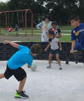 Children playing in a gaga ball pit using a 26 Foot Commercial Grade Recycled Rubber Interlocking Flooring Kit, easy install mat system.