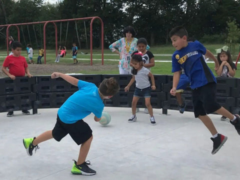 Children playing in a gaga ball pit using a 26 Foot Commercial Grade Recycled Rubber Interlocking Flooring Kit, easy install mat system.