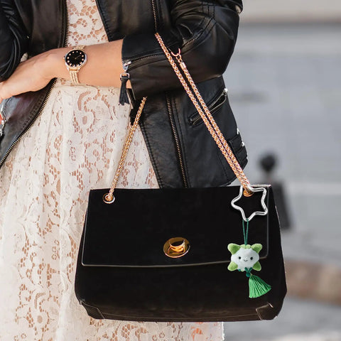Woman holding black purse with Two Pack Aluminum Star Shaped Carabiners With Key Rings attached, small silver snap hook for keys and wallets.