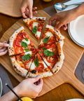 Heavy Duty 14 Inch Bamboo Pizza Peel And Wooden Spatula Paddle For Backyard Cookouts, serving freshly sliced pizza.