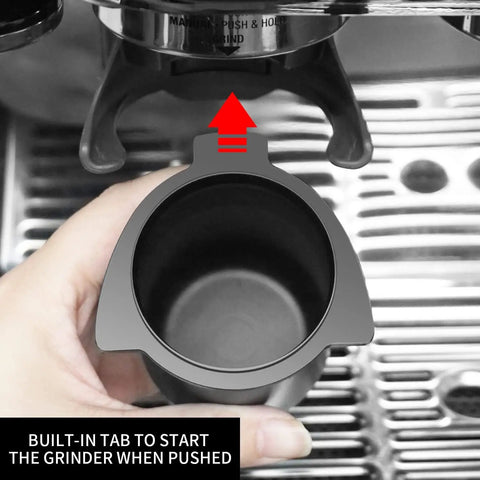 Hand holding 54mm Espresso Dosing Cup for Portafilter with Grinder Activating Ring Matte Black grounds cup under grinder.