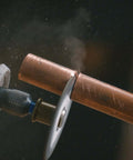 Dremel EZ456 fiberglass-reinforced cut-off wheel attached to a rotary tool cutting copper pipe (side view)