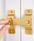 Gold Stainless Steel Barn Door Latch For Gate Bi Fold Sliding Door Lock on white surface being installed by hand, 4.33 x 3.23 inches.