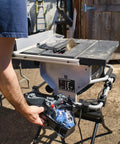 Heavy Duty Compact Table Saw With Patented Skin Contact Safety System And Precision Rack Pinion Fence For Rock Solid Job Site Performance 15 Amp Motor 120 Volt Setup showing operator's hand adjusting settings.