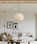 Twenty Inch Off White Japanese Rice Paper Lantern Plug In Pendant Light With Adjustable Cord Sets hanging above a cozy living room couch.