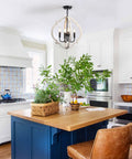 Farmhouse Orb Wood Chandelier 4 Light Pendant illuminating a rustic kitchen with blue island and leather chairs.