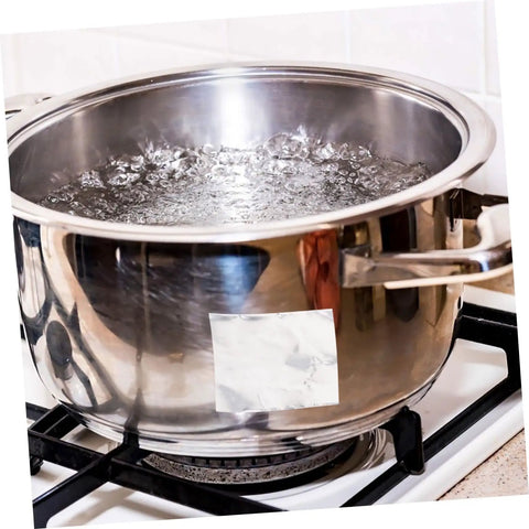 Stainless steel pot with water boiling on a gas stove in a kitchen setting.