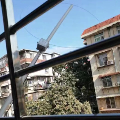 Beefed Up Active Loop Antenna for 0.5 to 30 MHz on window with urban buildings view, featuring USB power and rainproof build for HAM radios