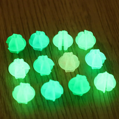 12 green glow-in-the-dark beads on a wooden surface from 36 Pack Glow In The Dark Luminous Bicycle Wheel Spoke Wrap Tubes In Colorful Plastic