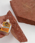 Person applying Heavy Duty Waterproof Polyurethane Glue In Rich Brown on brick for secure bonding during home project.