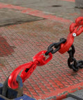 Rugged As Nails 3/8 Inch Swivel Self Locking Eye Hook, Grade 80 Forged Alloy Steel, 6945 Lbs Working Load Limit, red hook attached to black chain.