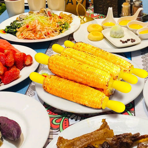 Six Pairs Stainless Steel Corn Holders Set for Easy Grub Grabs on the Cob Yellow Corn on the Cob Skewers on a dining table.