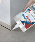 Hand applying Pro Grade Rock Solid Concrete Crack Sealant Waterproof Masonry Repair Adhesive along a concrete joint.