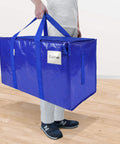 Person holding a blue 8 Pack Extra Large Moving Bag with zippers and carrying handles, 27x14x15 inches, 100Lb capacity.