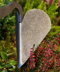 Close-up of Drop Grip Hand Plow for Raised Beds, ash wood handle, steel head digging soil among plants