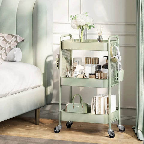Three Tier Rolling Cart Storage Organizer With Metal Wheels Pegboard Hooks And Bins For Bathroom Kitchen Office Nursery And Craft Rooms placed beside bed, filled with books, toiletries, and decor.