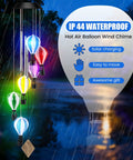 Solar Wind Chimes Outdoor Decor With Hot Air Balloon Lights Waterproof Garden Patio Lighting Lit At Night Perfect Gift For Mothers Day Mom Grandma Birthday. Multicolor hot air balloons glow at night in rainy garden setting.