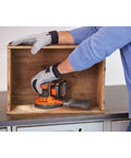 Person using Cordless Orbital Sander With 12,000 OPM For Fast Material Removal on a wooden box, includes battery and charger.