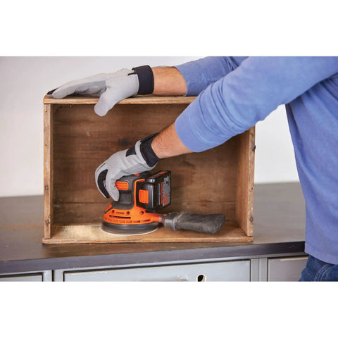 Person using Cordless Orbital Sander With 12,000 OPM For Fast Material Removal on a wooden box, includes battery and charger.