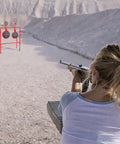 Person aiming at Double Spinner Shooting Targets Three Eighths Inch Thick Steel Auto Reset Target System with mountain backdrop.