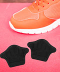 Premium Heel Grips Insert Kit locks your shoes in place. Black foam heel pads for sneakers on pink background.