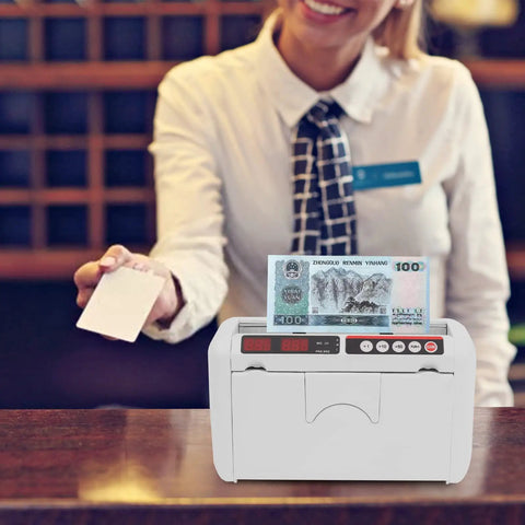 Portable Rechargeable Cash Counting Machine With UV And MG Counterfeit Detection on a counter with cashier in background