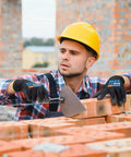 Worker wearing 12 Pairs PU Coated Cut Resistant Work Gloves With Tough As Nails Grip For Warehouse Woodworking And Construction Men And Women Full Finger Touchscreen Compatibility ANSI A1 Protection using trowel on brick wall