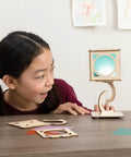 Child interacting with Levitating Lantern STEM Kit For Kids 9 Plus, gravity defying wooden lantern with tensegrity design on table.