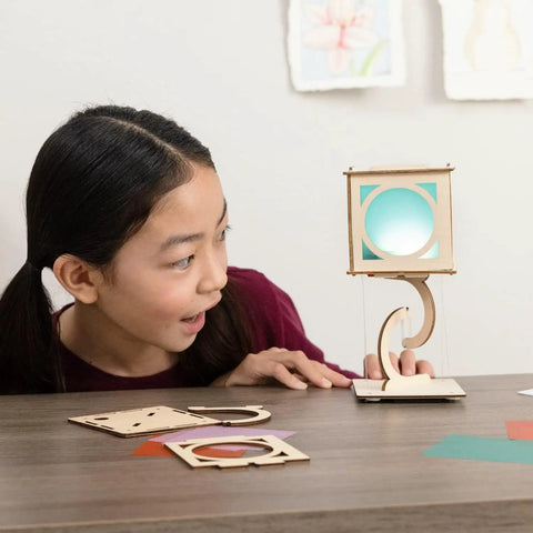 Child interacting with Levitating Lantern STEM Kit For Kids 9 Plus, gravity defying wooden lantern with tensegrity design on table.