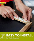 Hands applying Medium Picture Hanging Strips, 52 Pairs (104 Strips), Damage Free Wall Decor Holds Up To 12 Lbs with 4 Pairs, Easy To Use.