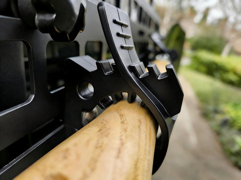 Close-up of Rugged Truck Shovel Holder with Quick Release Rubber Clamp mounted on a roof rack holding wooden handle tool.