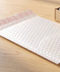 White Bubble Mailers 30 Pack 6x8 Inch Padded Envelopes For Small Biz Shipping laid on wooden table with self-seal feature visible