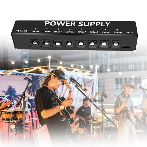 Eight Isolated Outputs Pedalboard Power Supply with independent short circuit protection overlaying a live music gig scene