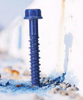 Heavy Duty Blue Hex Head Concrete Screw Anchors PTFE Coated Carbon Steel 1/4 In X 2-3/4 In 200 Pc Bulk Pack inserted into concrete.