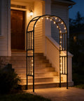 Go-To 6.9x7.9 Ft Square Tube Garden Arbor Trellis With Twisted Metal Design illuminated at night by entrance