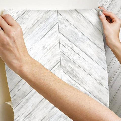 Hands applying White And Tan Herringbone Wood Look Peel And Stick Wallpaper For Renters And Homeowners, Removable Vinyl
