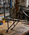 Ultra Light Front Fork Cargo Rack With Side Rails For Bikepackers And Bikepacking Steel V Brake Compatible Lightweight Mounting System Secure Three Point Fixation Front Wheel Gear Carrier on workshop table