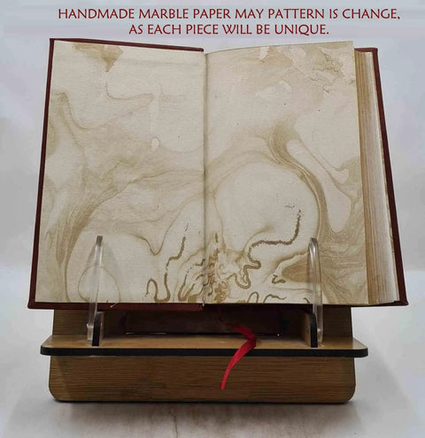 Open marble-patterned page in 'From Raw Wool To Finished Goods: A Rugged Premium Leather Bound Guide To Wool Crafting, 186 Page Collector’s Edition, English, By Hunter J A, Released 2024' displayed on a wooden stand.