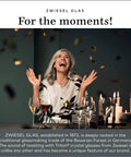 Woman celebrating with Tritan crystal glasses, surrounded by candles and confetti, showcasing Zwiesel Glas elegance.
