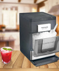 Snag This No Hassle Countertop Ice Maker That Cranks Out 33 Pounds Of Chewable Nugget Ice Daily Featuring A Sleek Black Exterior And Premium Steel Accents For Your Ultimate Home Bar Setup with ice scoop and a drink.