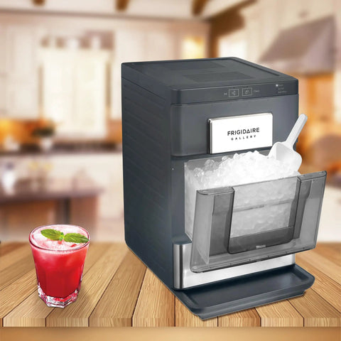 Snag This No Hassle Countertop Ice Maker That Cranks Out 33 Pounds Of Chewable Nugget Ice Daily Featuring A Sleek Black Exterior And Premium Steel Accents For Your Ultimate Home Bar Setup with ice scoop and a drink.