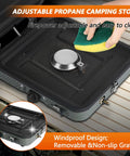 Two-Burner Propane Camp Stove With Grill And Carrying Bag, showing a removable grate being cleaned with a sponge.