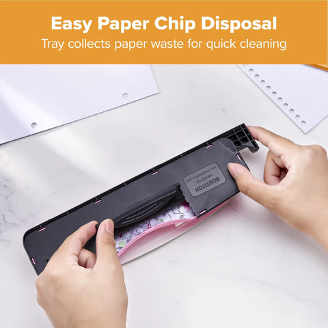 Hands displaying tray on InCOURAGE 12 Reduced Effort 3 Hole Punch For Office And School Use with pink finish and ruler guide.