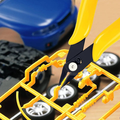 Yellow-handled deburring tool with black jaws trimming plastic model sprue.