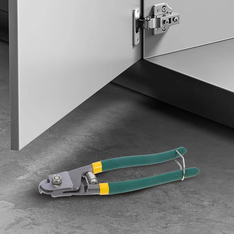 Heavy Duty Multi Function Wire Stripping Pliers And Cable Cutter Crimping Tool With Ergonomic Grip on concrete floor beside cabinet.