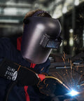 Welder using Auto Darkening Welding Helmet With Flip Front Viewing Area 3.86 By 1.61 Inches, Adjustable Headgear, Shade 11 during welding.